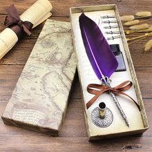 Feather pen set with purple feather and decorative elements in a box on a wooden surface.
