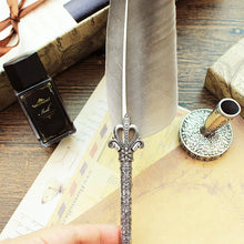 Decorative silver feather quill pen with ink bottle on a wooden surface