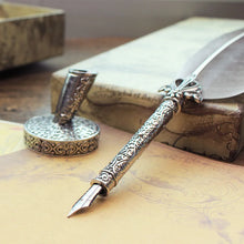 Decorative quill pen with ornate handle on a textured surface