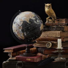 Vintage-style globe on books with an owl and glasses in the background