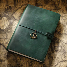 Green leather notebook with an anchor charm on a vintage map background