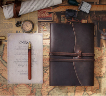 Brown leather journals on a vintage map with a cup of coffee, pen, and other items.