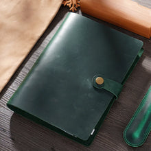 Green leather notebook with a gold button on a wooden surface