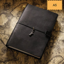 Black leather notebook with a charm on a vintage map background