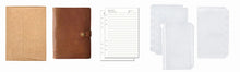 Collection of stationery items including a brown leather cover, a lined notebook, and clear plastic covers on a white background.