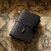 Black leather notebook with a charm on an old map background