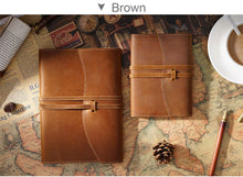 Two brown leather journals on a world map with a cup of coffee and pen.