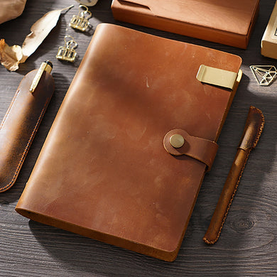 Brown leather notebook with pen on a wooden surface