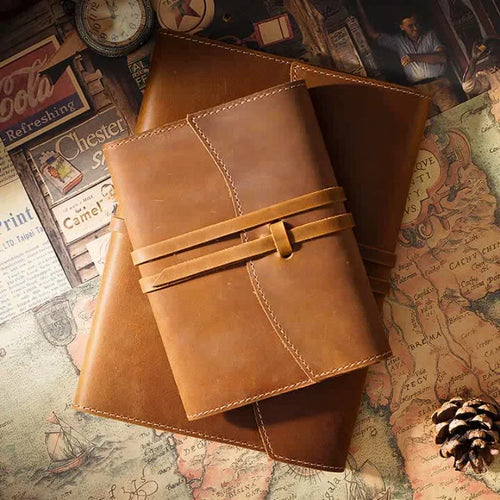 Brown leather journal with a strap on a vintage map background