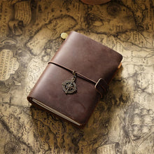 Brown leather journal with a compass charm on an old map background